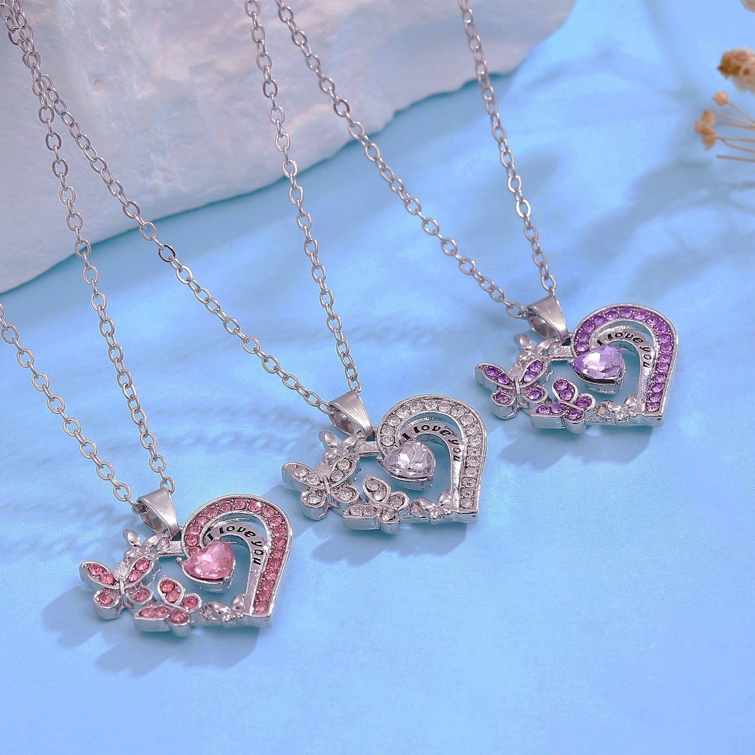 Three heart-shaped pendants on chains against a light blue background