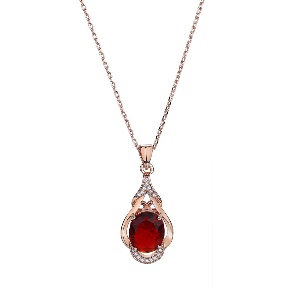 Rose gold necklace with a pendant featuring a red gemstone on a white background