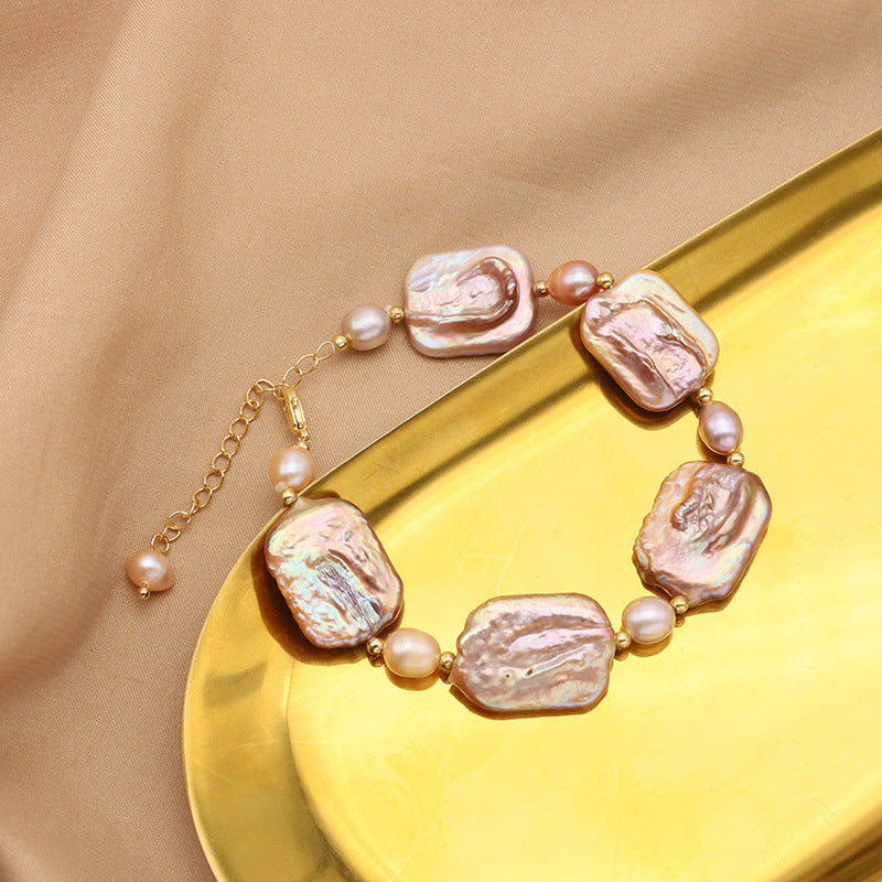 Pearl necklace with gold chain on a gold plate against a beige background