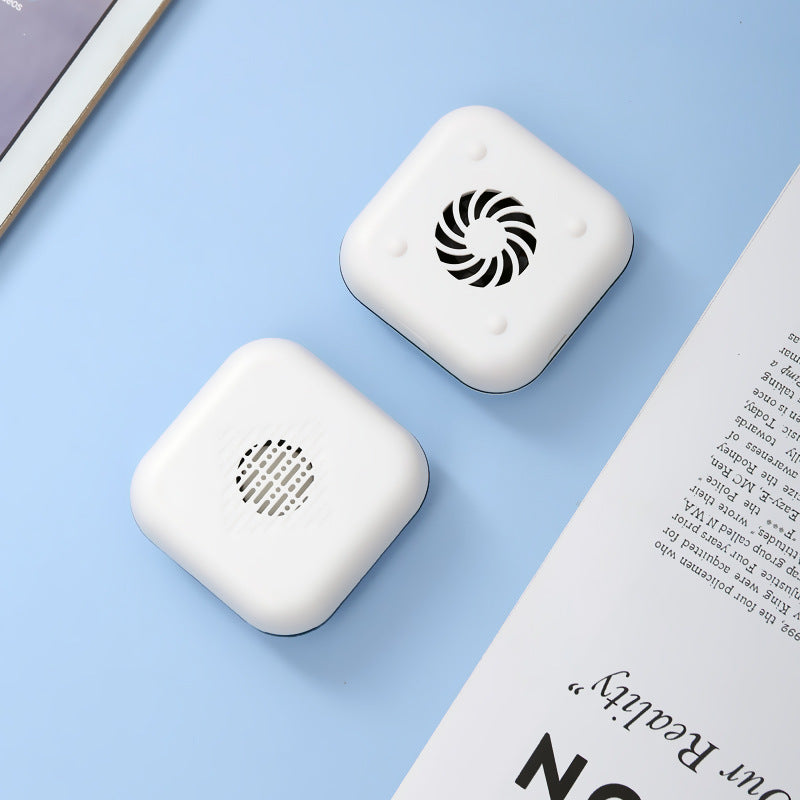 Two white square devices with circular patterns on a light blue surface next to an open book.