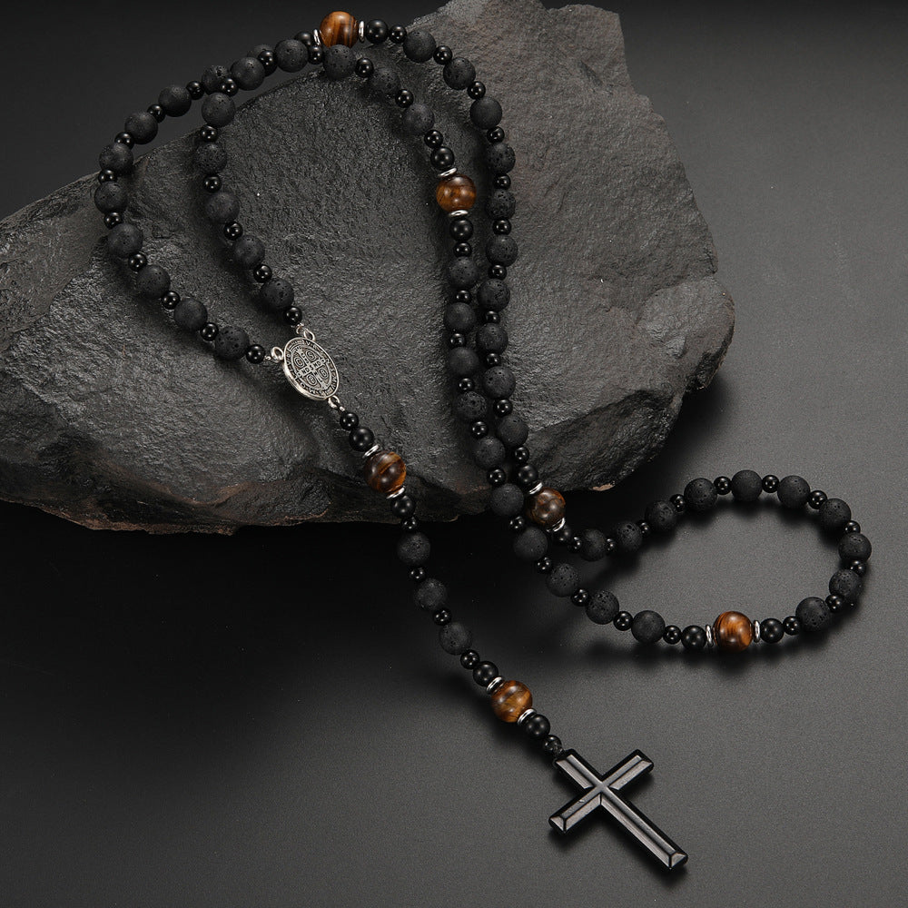 Black beaded rosary with a cross pendant on a dark stone surface