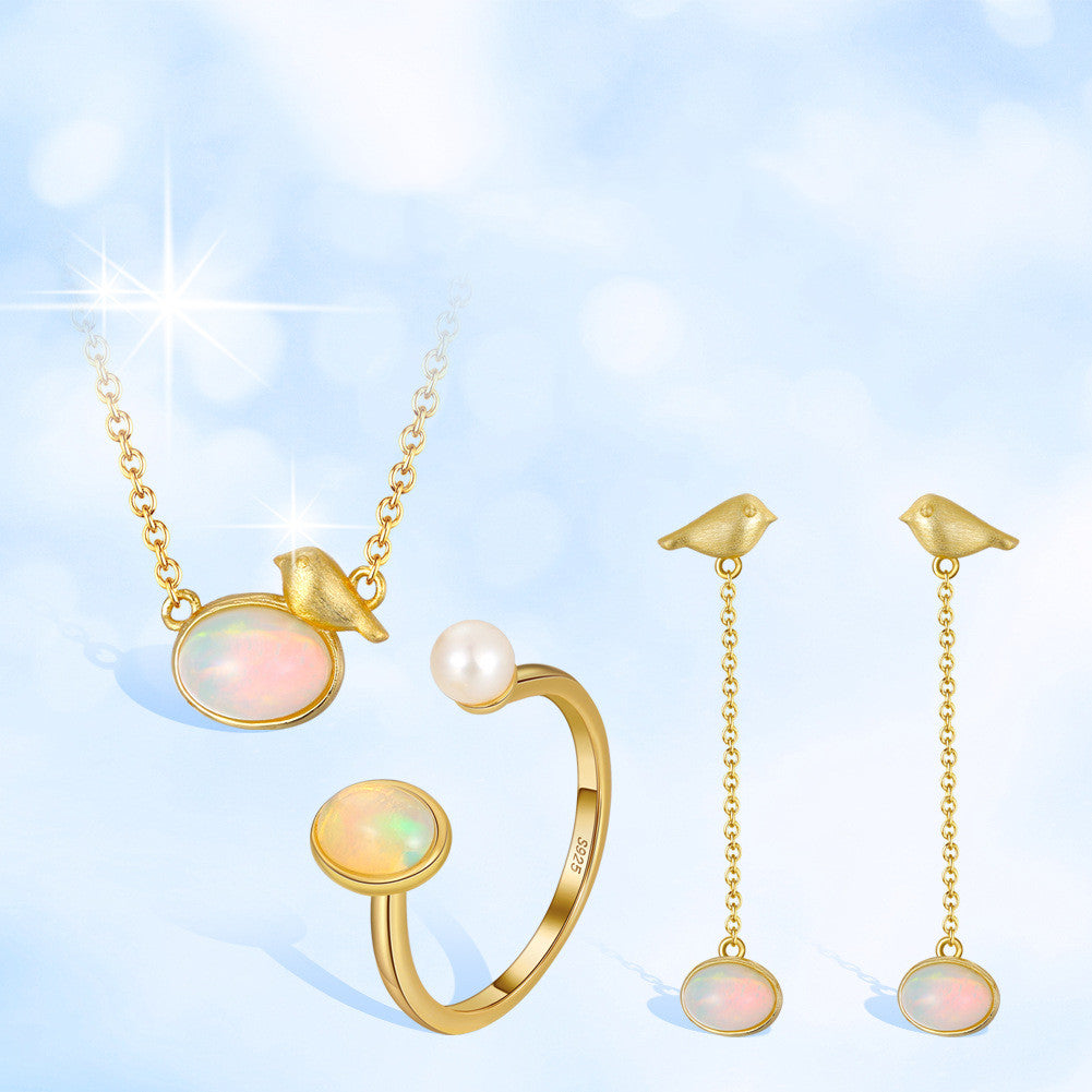 Gold jewelry set with necklace, ring, and earrings on a light blue background