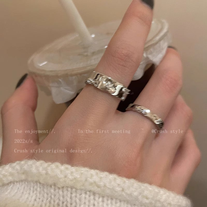 Hand wearing a silver ring with a blurred background