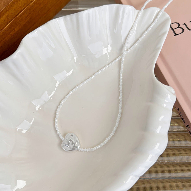 Silver necklace with a heart pendant on a white dish