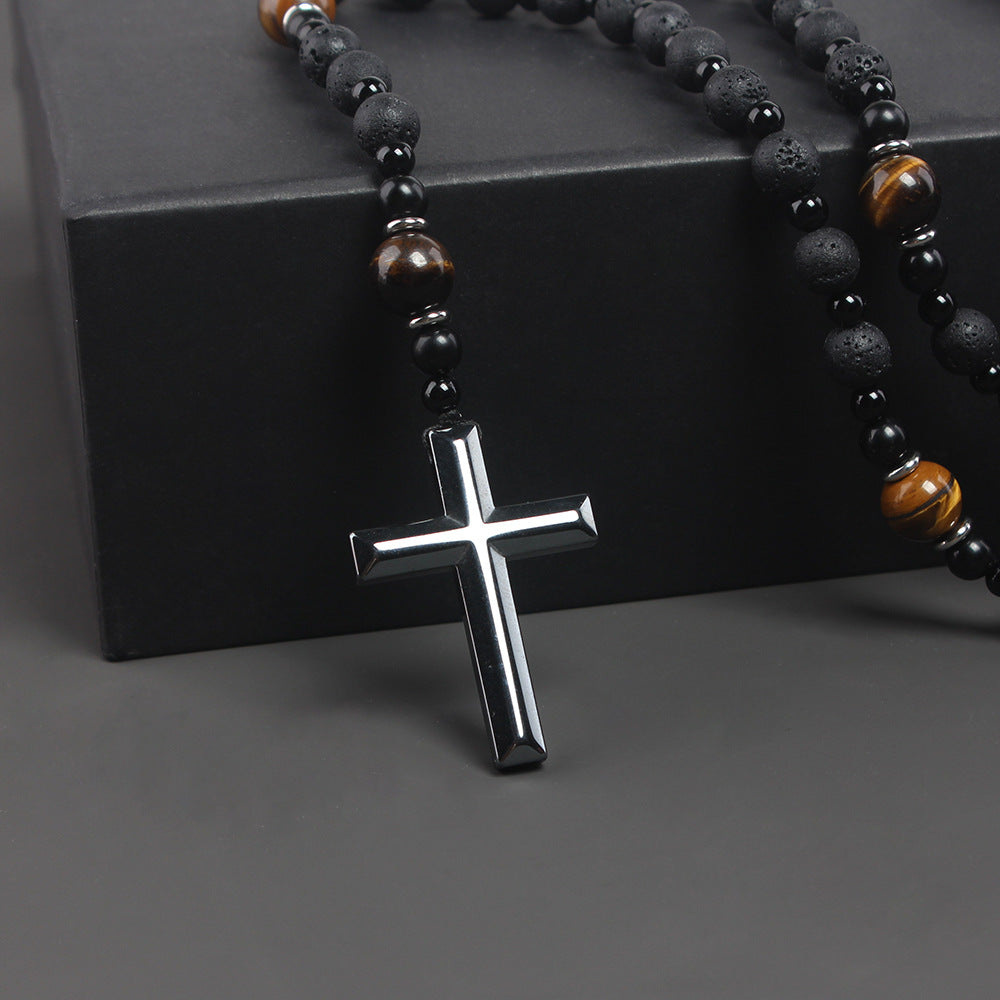 Necklace with black and brown beaded chain and silver cross pendant on a dark background
