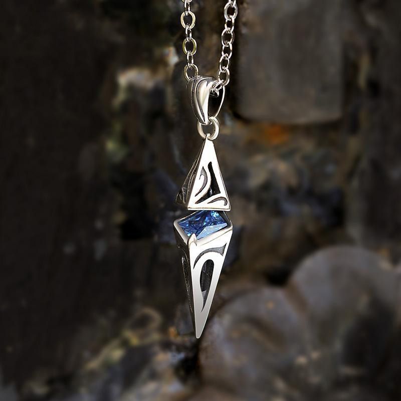 Silver pendant with blue gemstone on a chain against a natural stone background