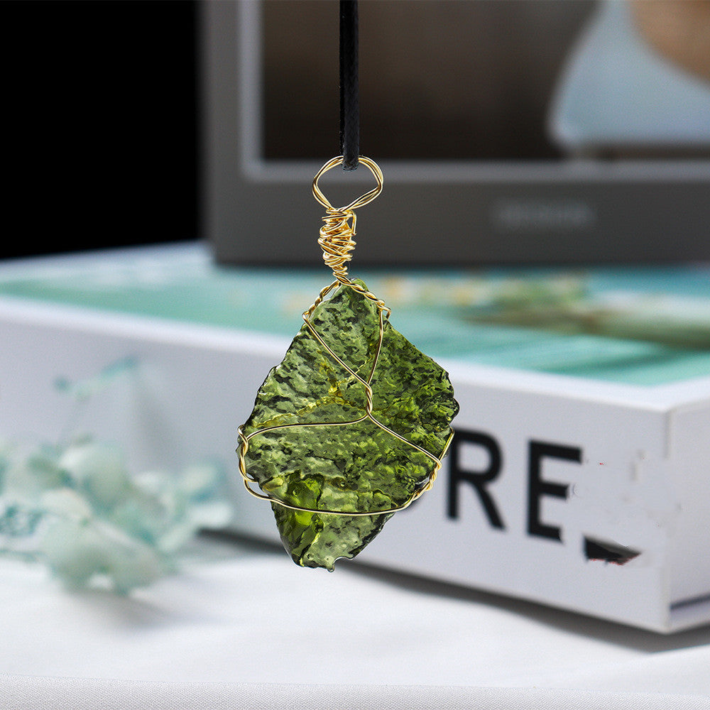 Green leaf-shaped pendant with gold wire wrapping on a blurred background