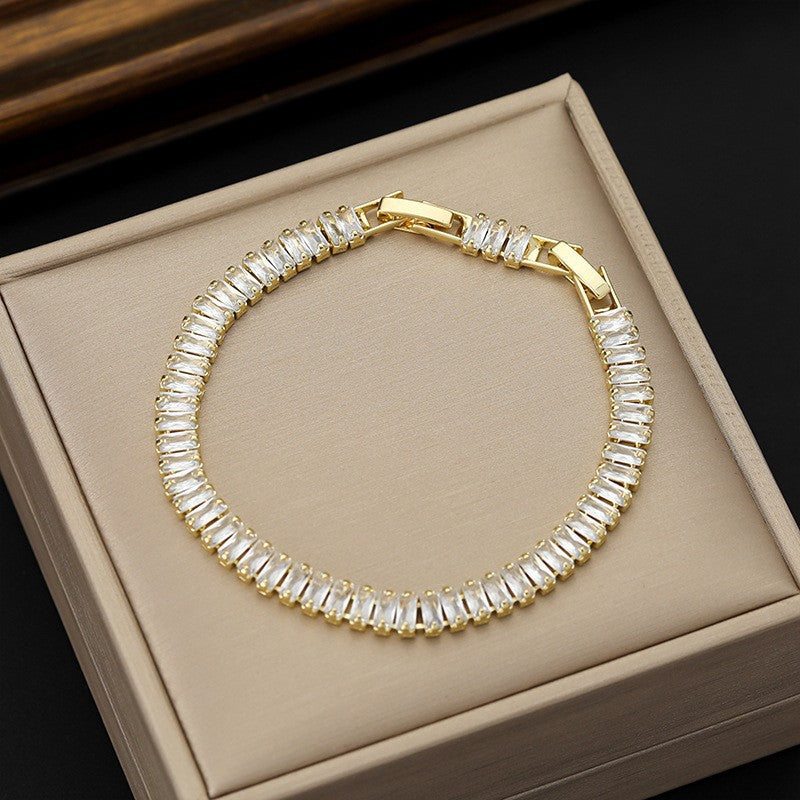 Gold bracelet with clear stones on a beige jewelry box