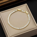 Gold bracelet with clear stones on a beige jewelry box