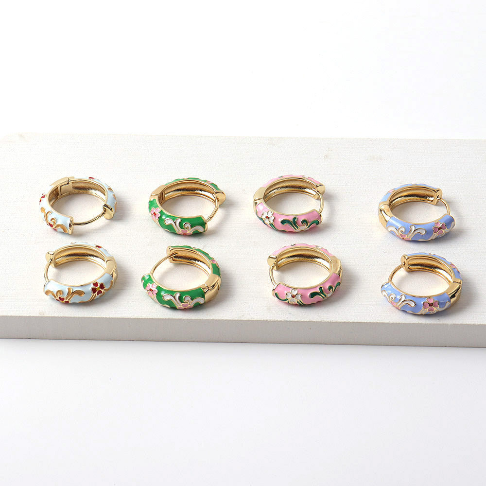 Set of small hoop earrings with floral designs on a white surface