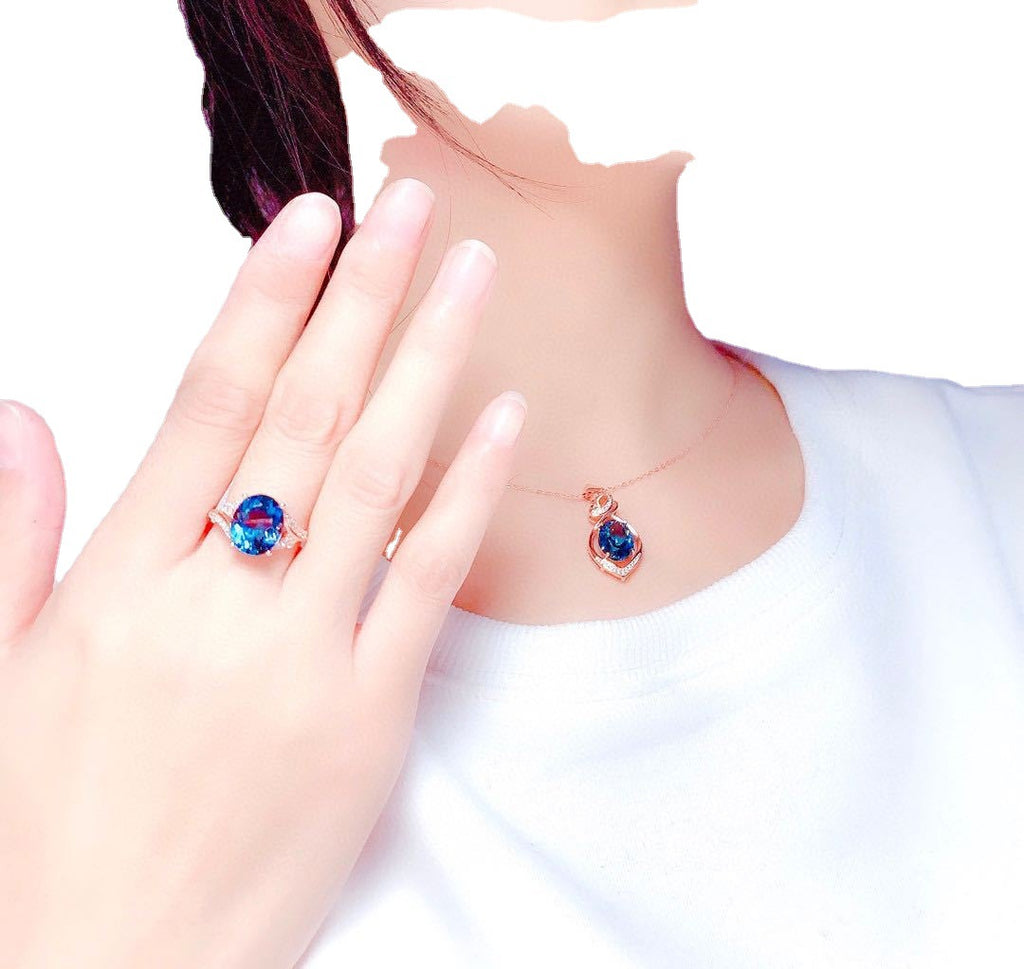 Close-up of a hand wearing a colorful ring with a matching earring on a white background