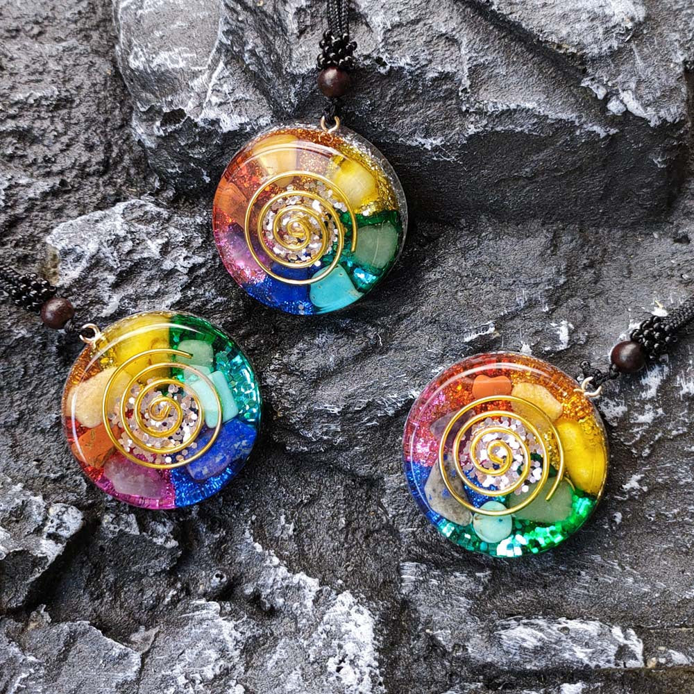 Three colorful spiral pendant necklaces on a stone surface