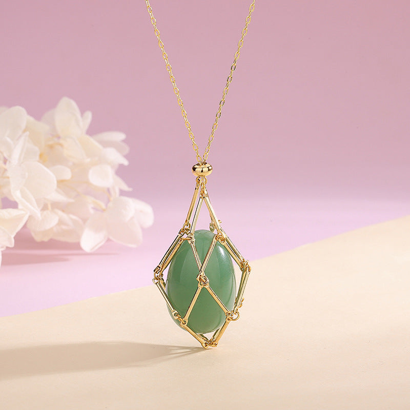 Gold necklace with a green gemstone pendant on a pink background