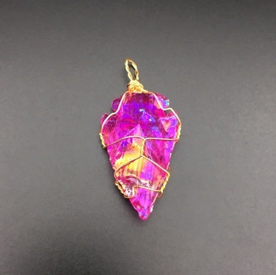 Pink crystal pendant with gold wire wrapping on a gray background