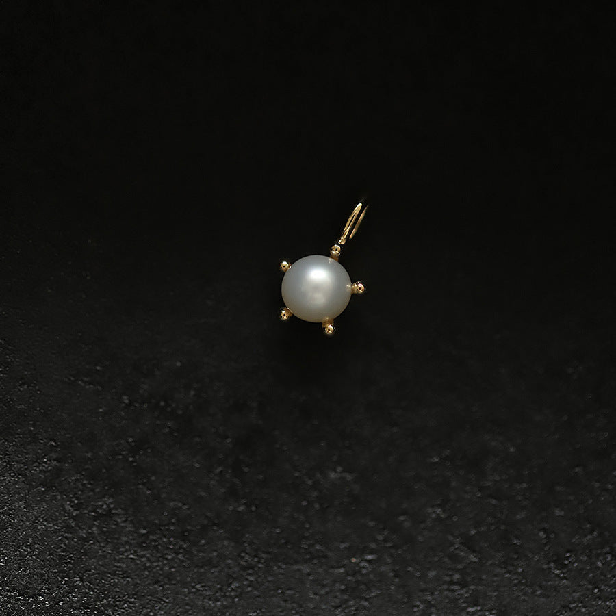 Pearl pendant with gold setting on a black background