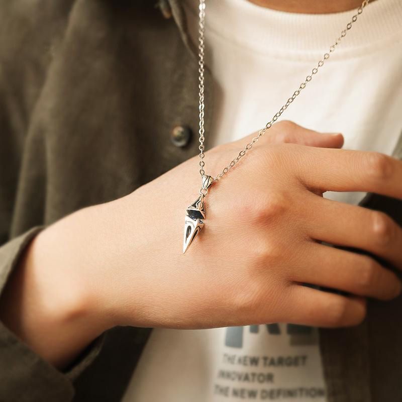 Hand wearing a silver necklace with a unique pendant, blurred background
