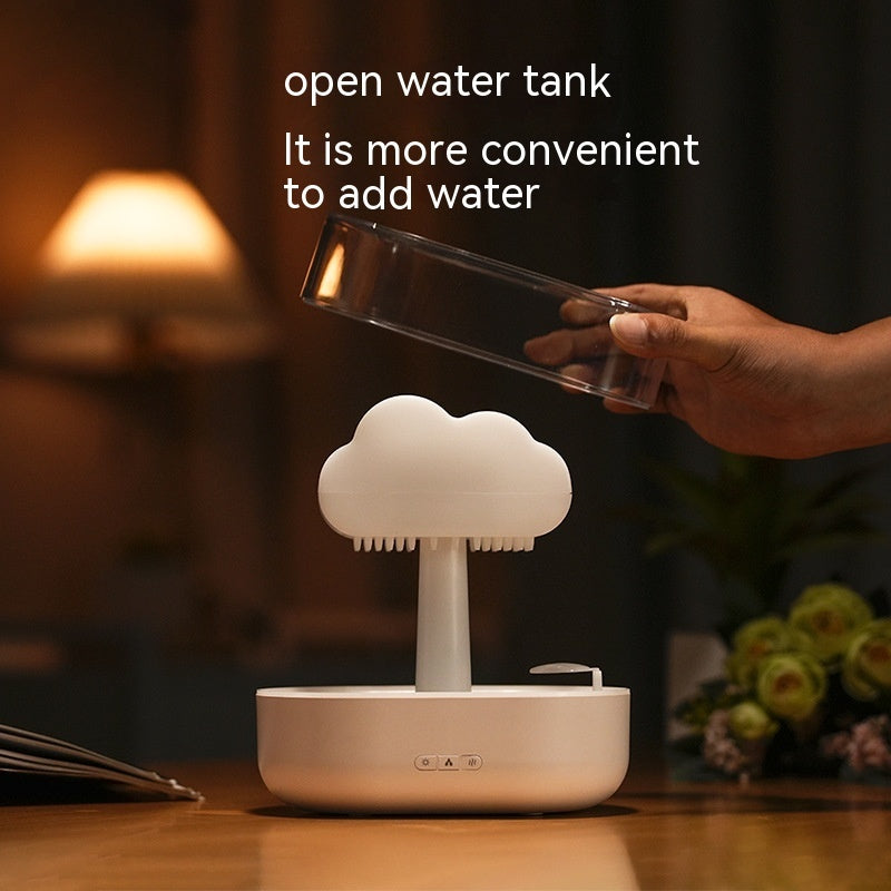 Hand holding a transparent container above a cloud-shaped water tank on a wooden surface.