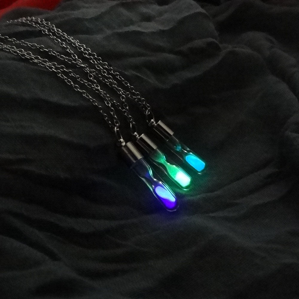 Necklace with glowing blue and green pendants on a dark fabric background