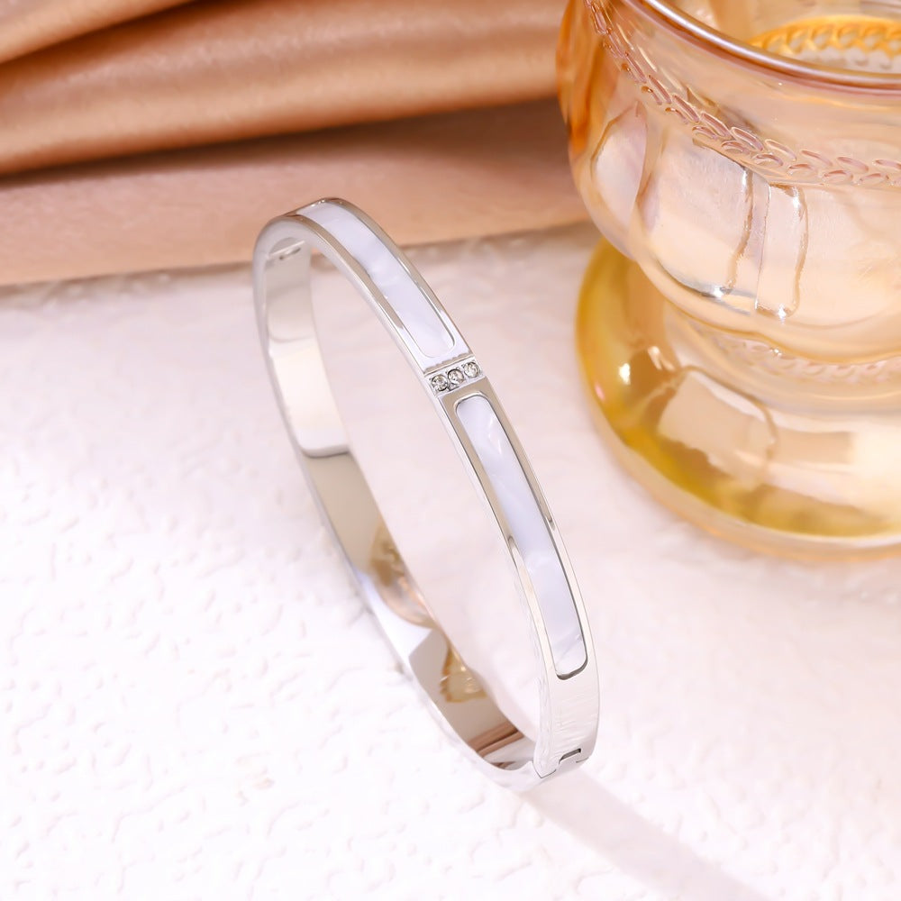 Silver ring on a soft fabric background with a blurred glass of tea in the background