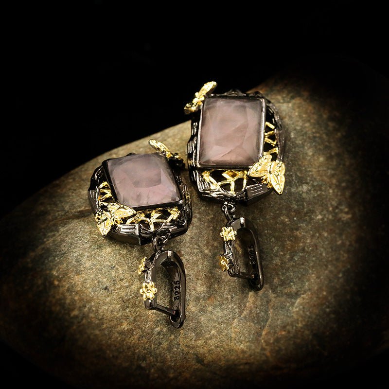 Pair of ornate earrings with gold accents on a textured surface