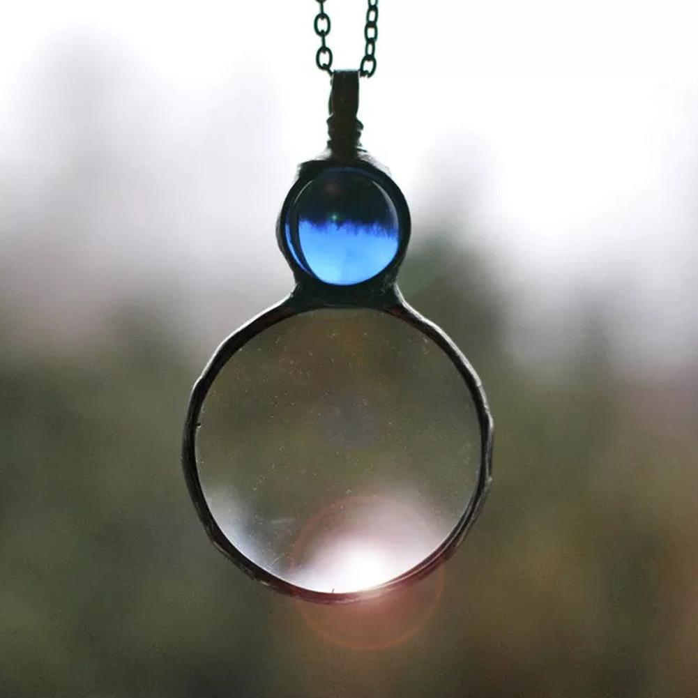 Glass pendant with a chain against a blurred natural background
