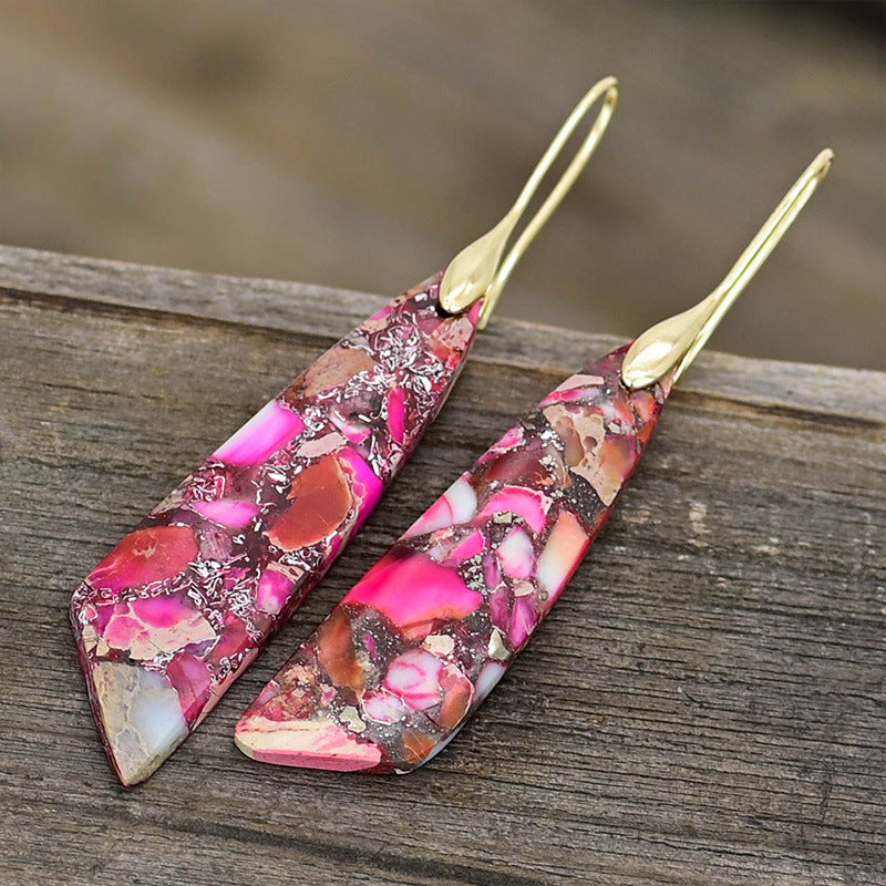 Pair of pink and gold earrings on a wooden surface