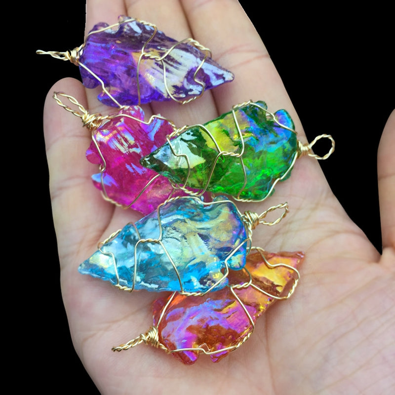 Colorful crystal pendants on a hand against a black background