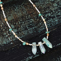 Necklace with turquoise beads and crystal pendants on a textured dark surface