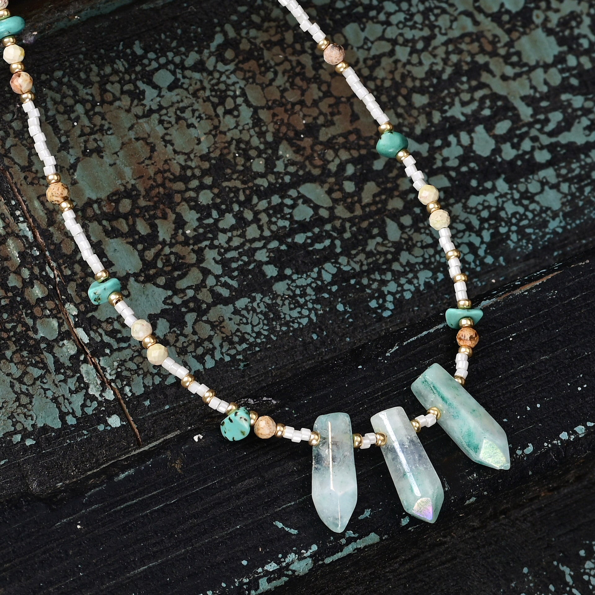 Necklace with turquoise beads and crystal pendants on a textured dark surface