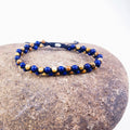 Beaded necklace with blue and beige beads on a stone surface