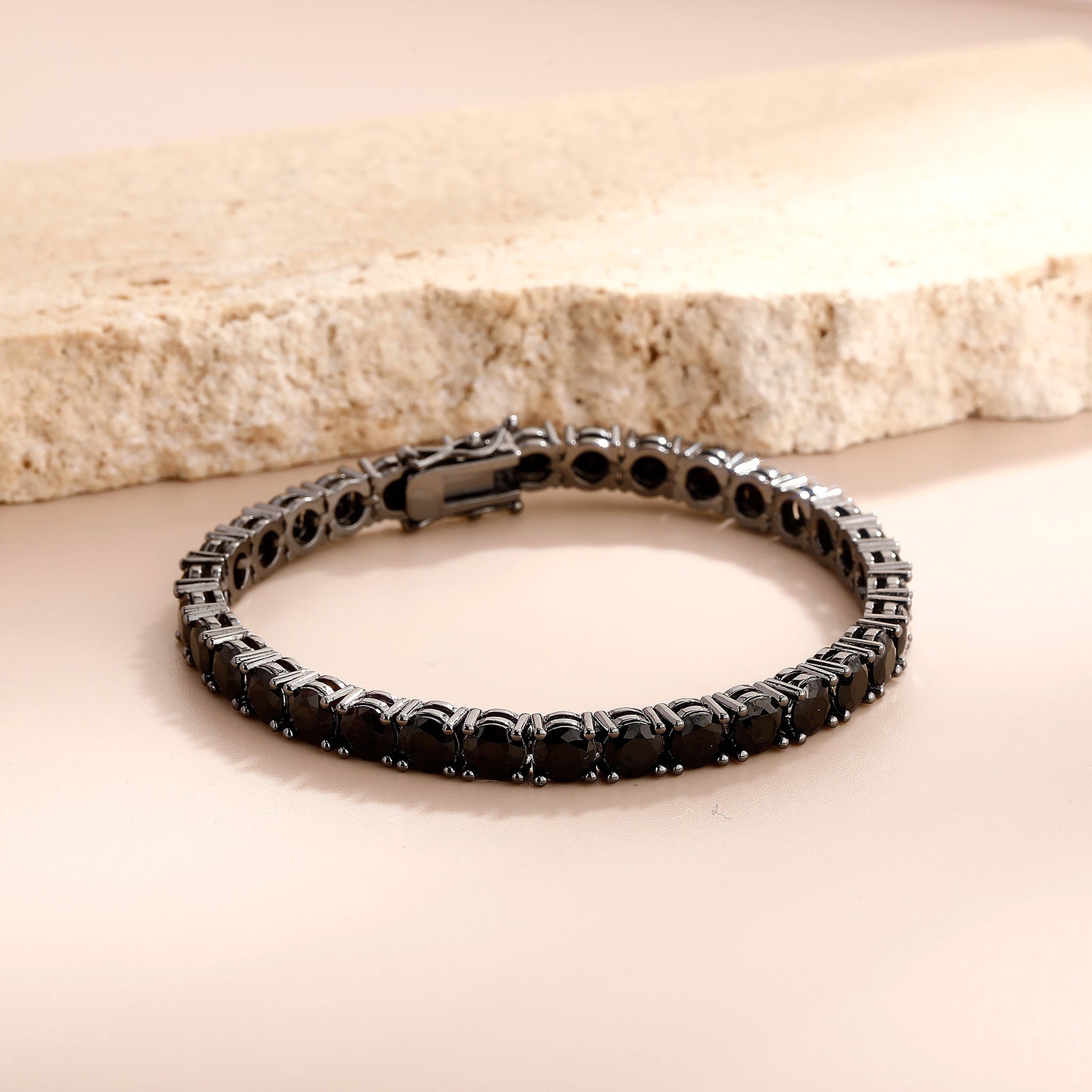 Black beaded bracelet on a beige surface with a neutral background