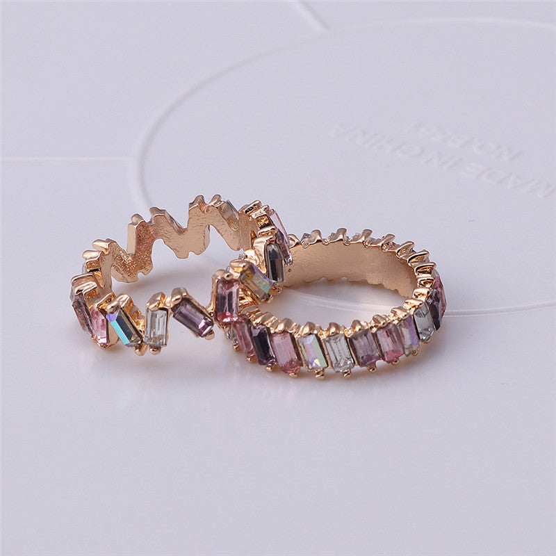 Gold ring with colorful gemstones on a light gray background