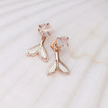 Rose gold mermaid tail earrings with clear gemstones on a marble background