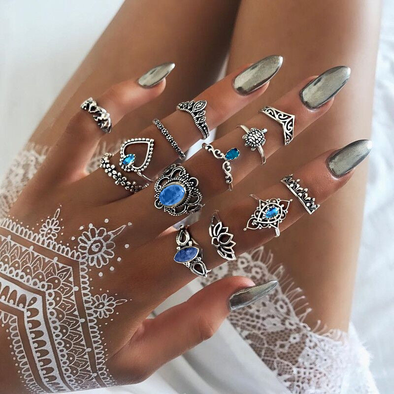 Hand wearing multiple silver rings with gemstones on a white background