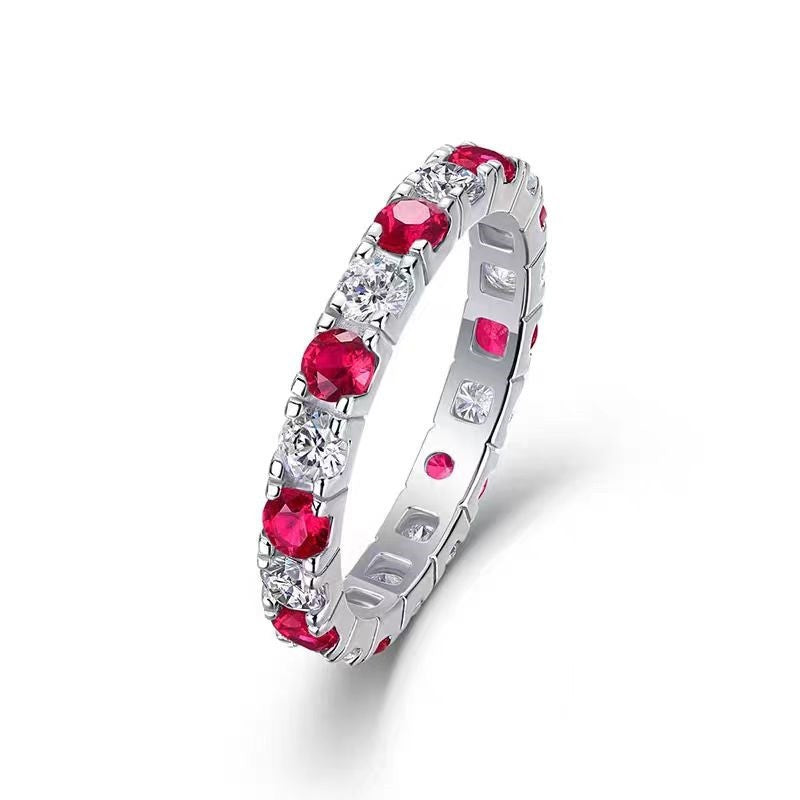 Silver ring with red gemstones on a white background