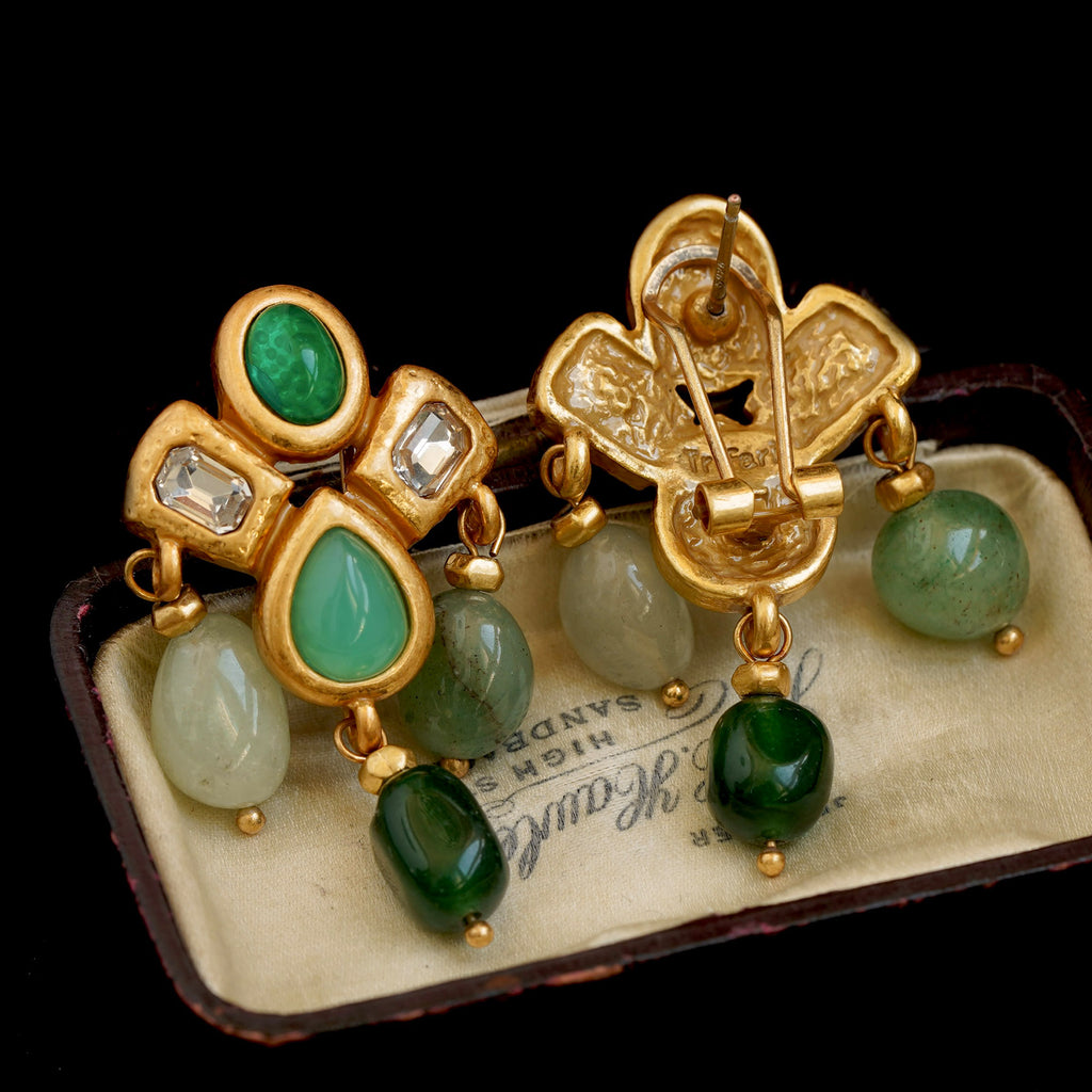 Gold earrings with green gemstones on a vintage box
