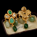 Gold earrings with green gemstones on a vintage box