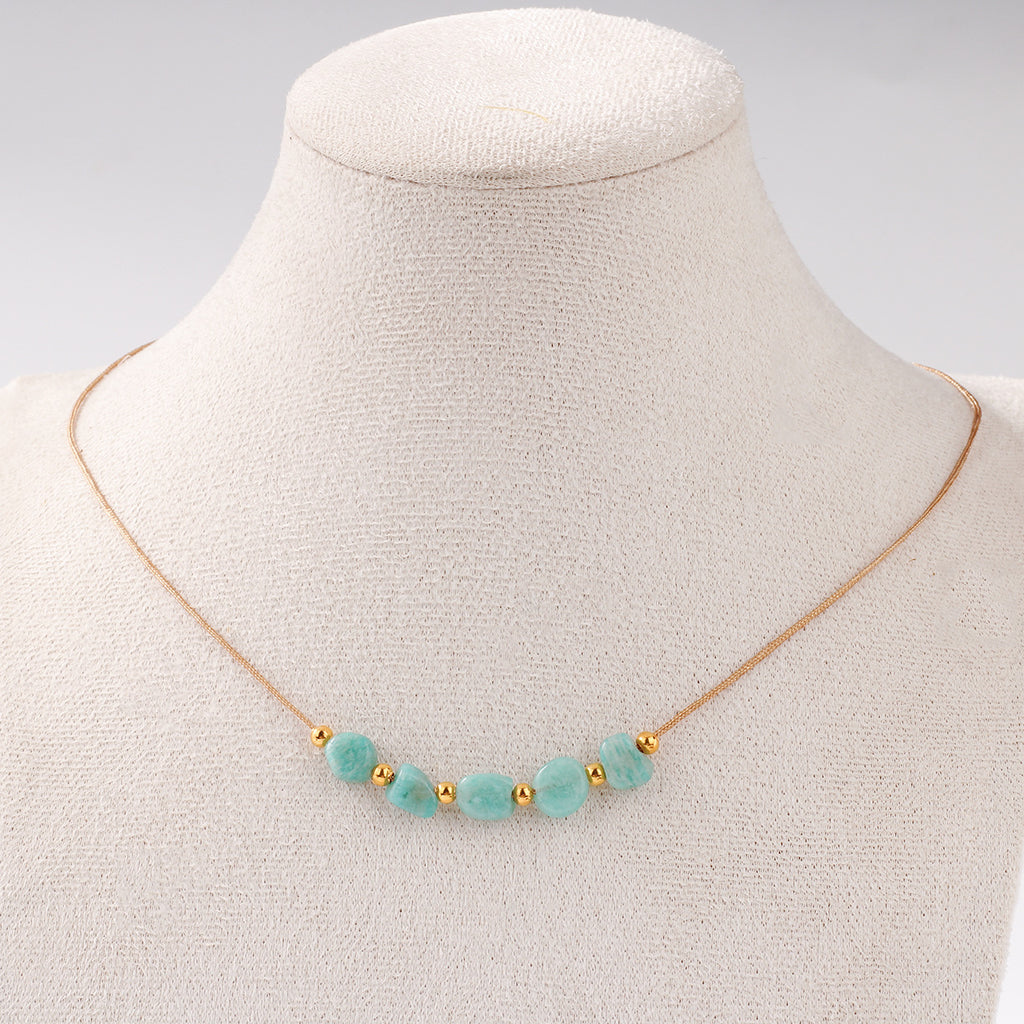 Necklace with turquoise beads and gold accents on a mannequin bust.