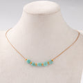 Necklace with turquoise beads and gold accents on a mannequin bust.