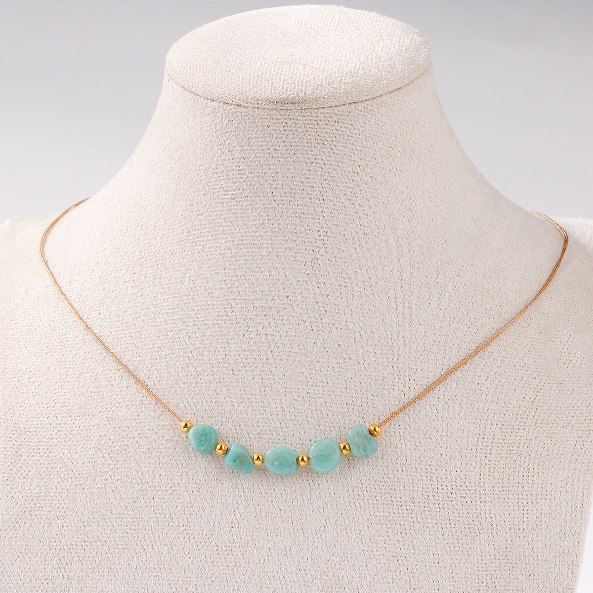 Necklace with turquoise beads and gold accents on a mannequin bust.