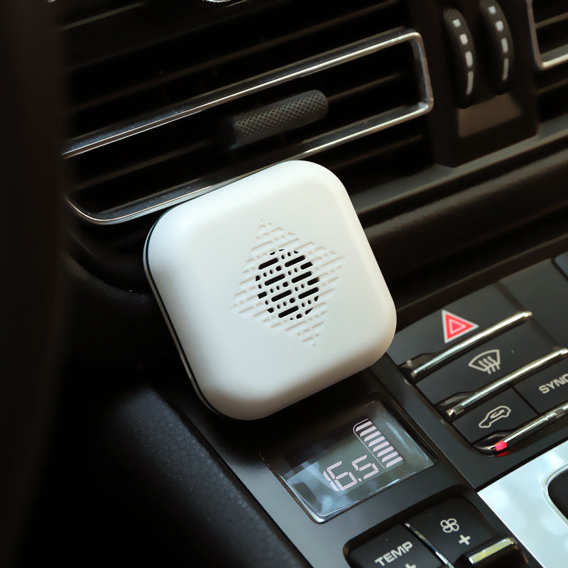 White car air freshener attached to a car's air vent.