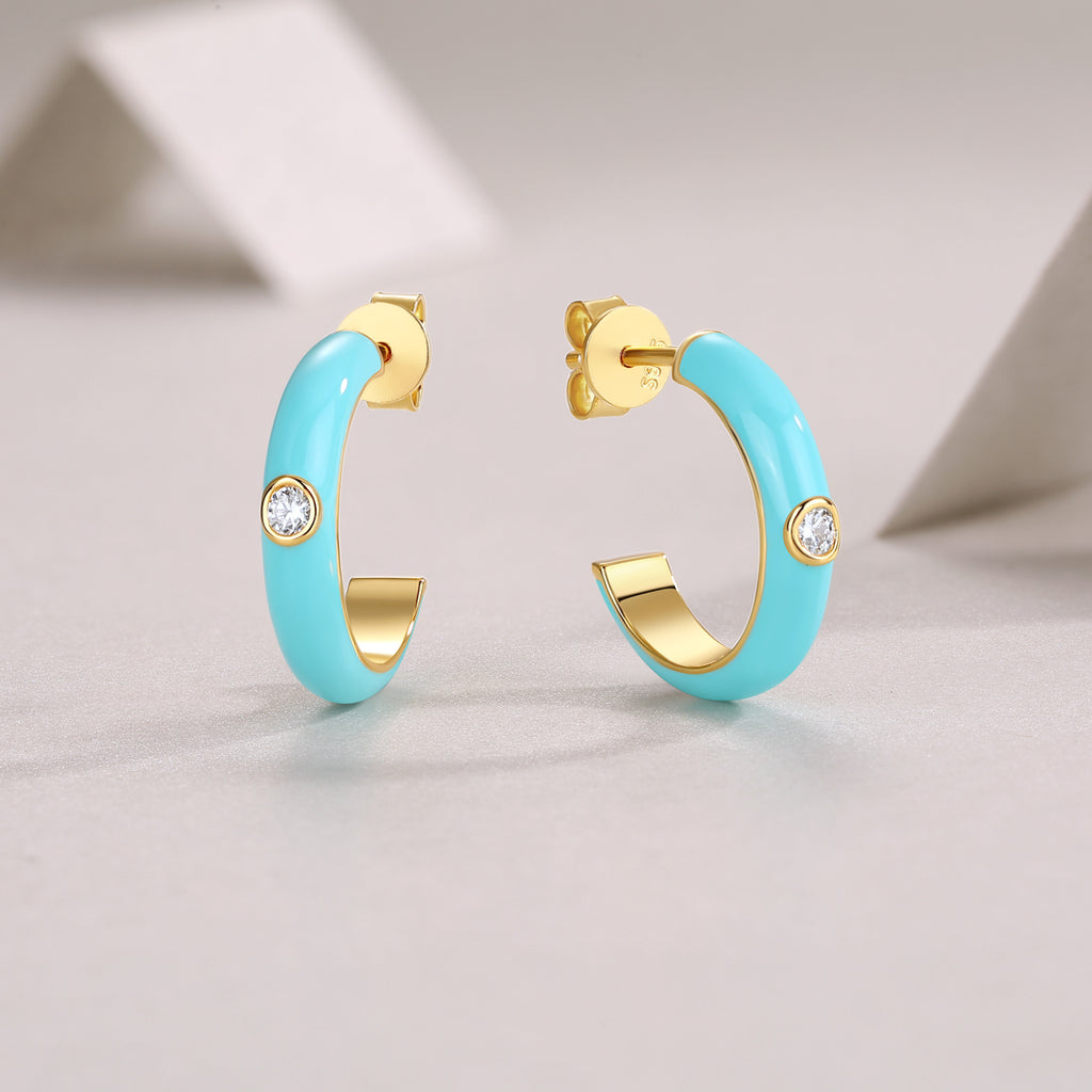 Turquoise hoop earrings with gold accents on a light gray background