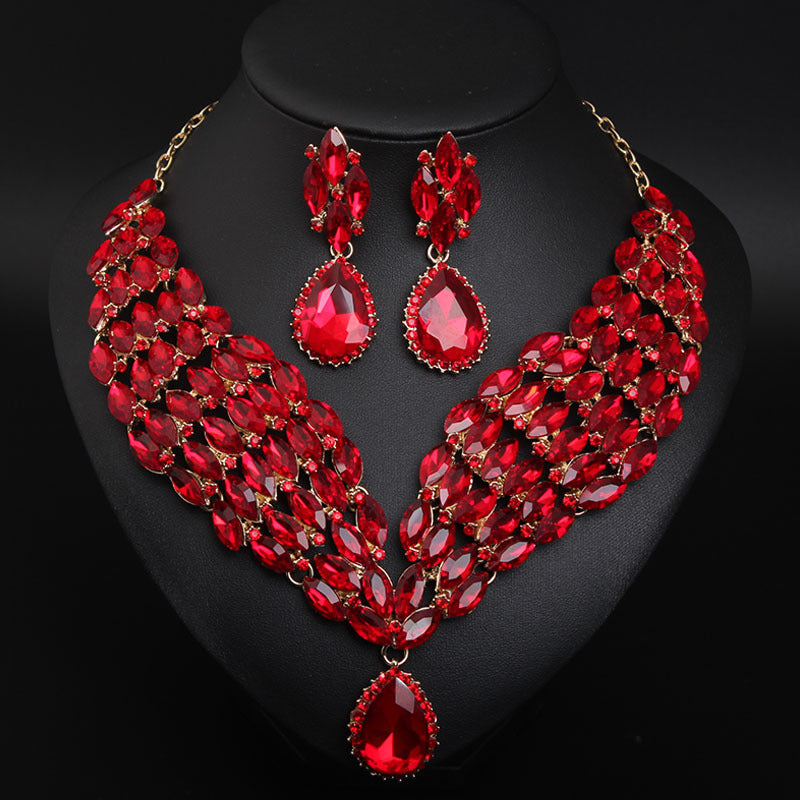 Red gemstone necklace and earrings set on a black stand
