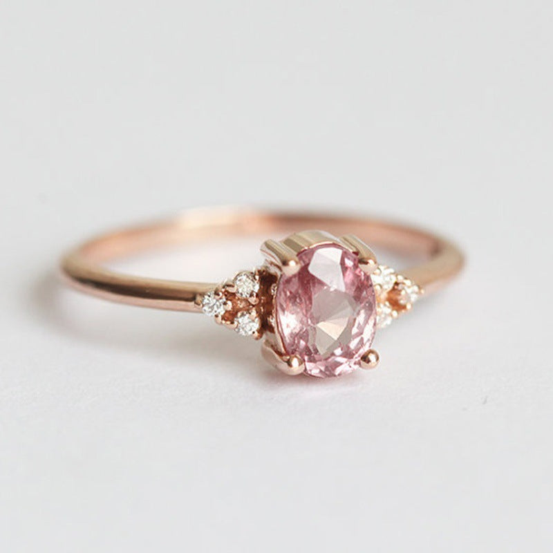 Rose gold ring with a pink gemstone on a light gray background