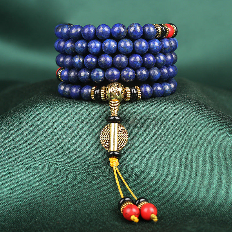 Blue beaded bracelet with gold and red accents on a green fabric background