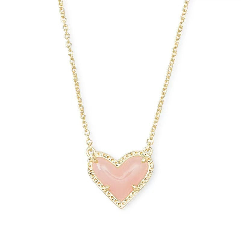 Necklace with a pink heart pendant on a gold chain against a white background