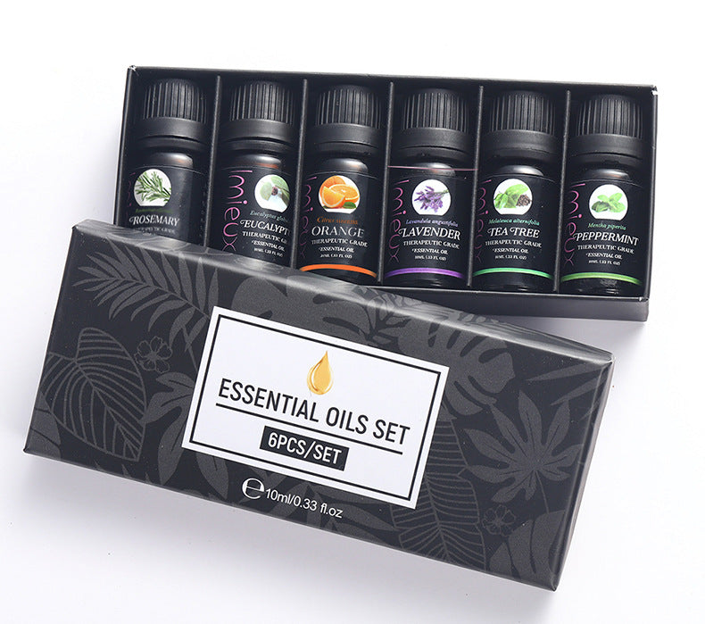 Set of essential oils in black bottles with labels, displayed in a decorative box on a white background.