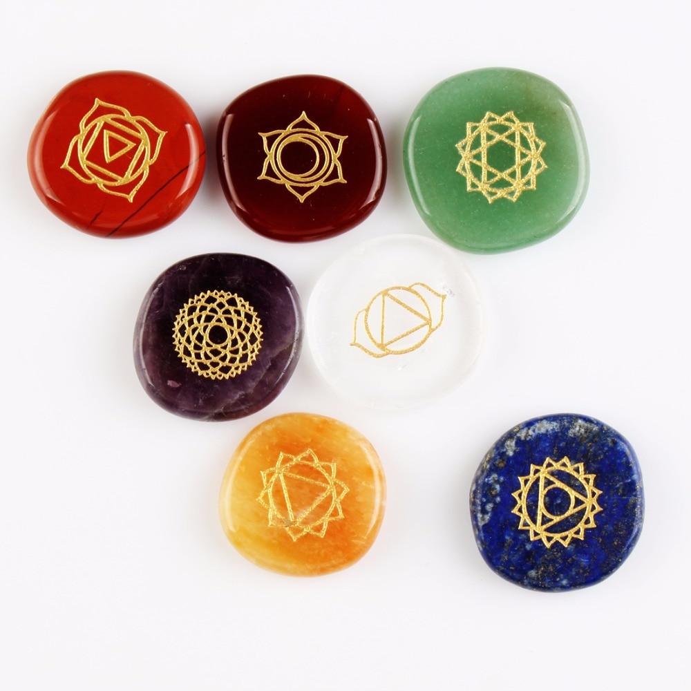 Set of seven chakra stones with gold symbols on a white background