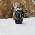 Black dog sculpture in front of a wooden background