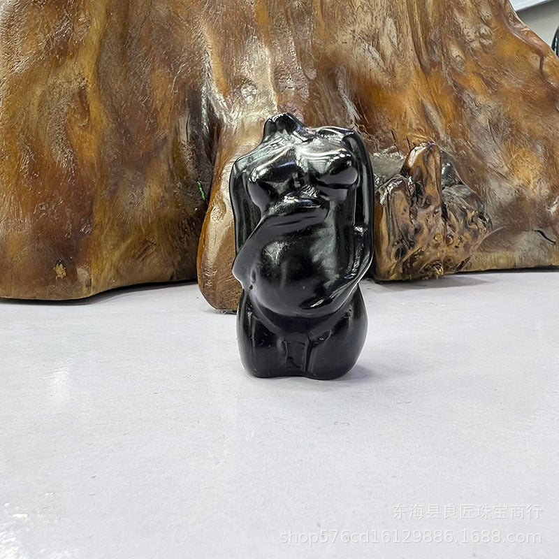 Black dog sculpture in front of a wooden background